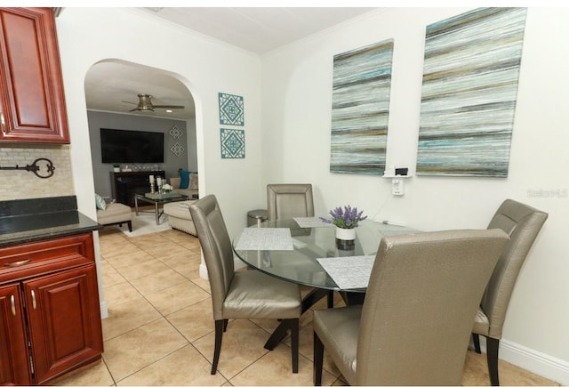 tiled dining space featuring ceiling fan and crown molding