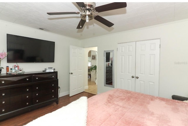 bedroom featuring ceiling fan, dark hardwood / wood-style flooring, a closet, and crown molding