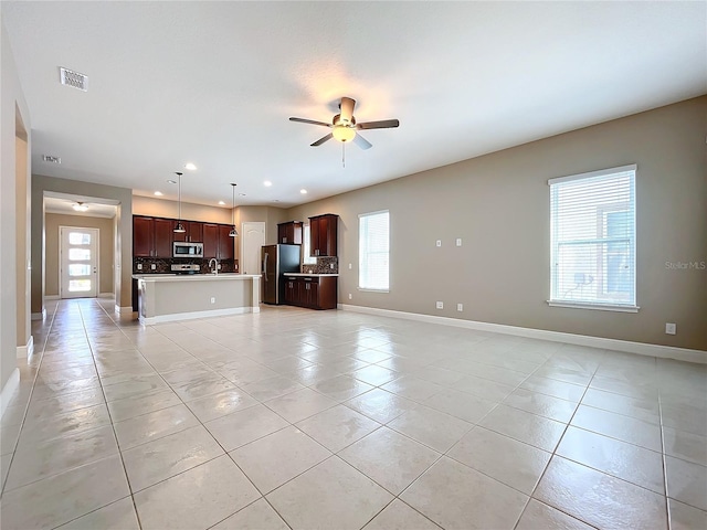 unfurnished living room featuring light tile patterned floors, sink, and ceiling fan