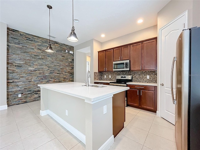 kitchen with decorative backsplash, pendant lighting, sink, a center island with sink, and stainless steel appliances