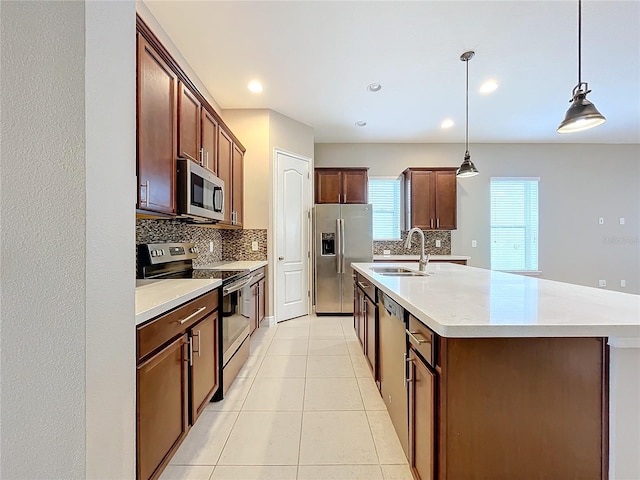 kitchen featuring decorative backsplash, decorative light fixtures, a center island with sink, light tile patterned flooring, and stainless steel appliances