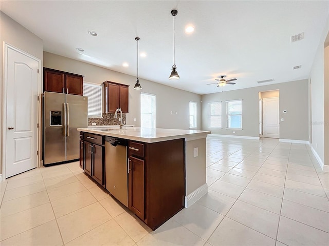 kitchen with stainless steel appliances, decorative backsplash, sink, a kitchen island with sink, and light tile patterned floors