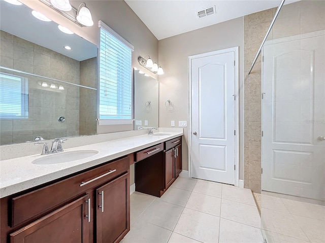 bathroom with tile patterned flooring, vanity, and tiled shower