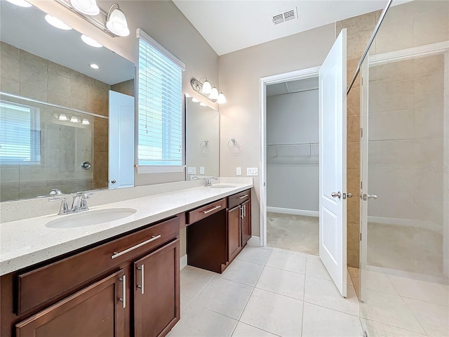 bathroom featuring tile patterned floors, a tile shower, and vanity