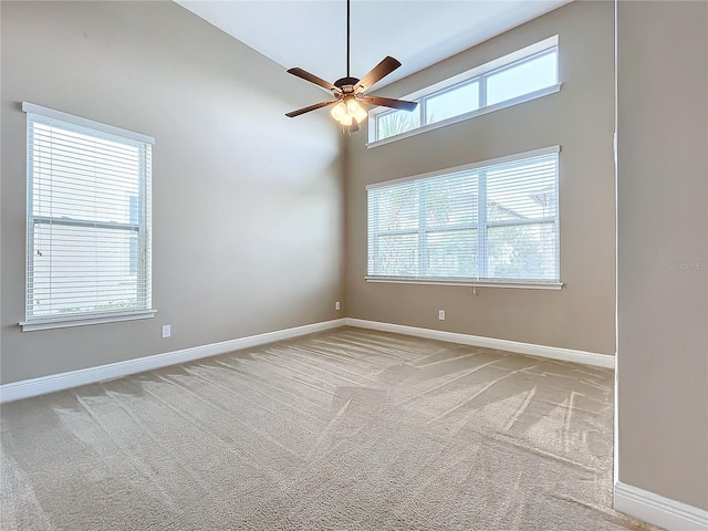 carpeted spare room featuring ceiling fan and high vaulted ceiling