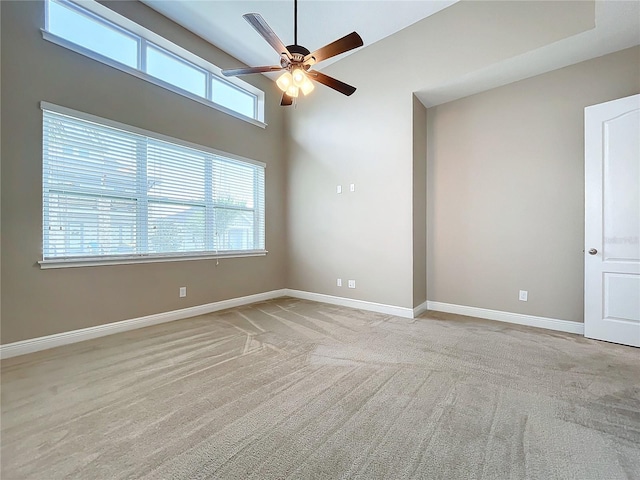 carpeted empty room featuring ceiling fan and a high ceiling