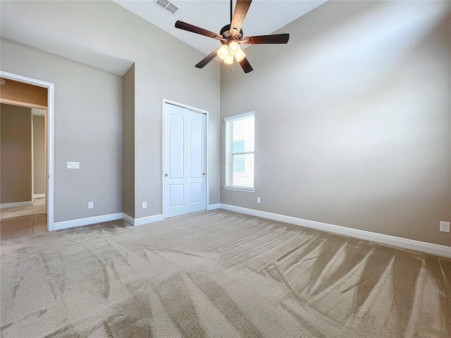 unfurnished bedroom featuring ceiling fan, high vaulted ceiling, a closet, and carpet flooring