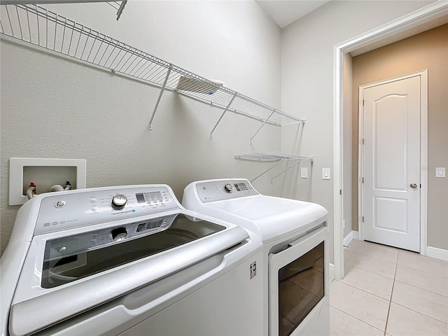 clothes washing area with light tile patterned flooring and washing machine and dryer