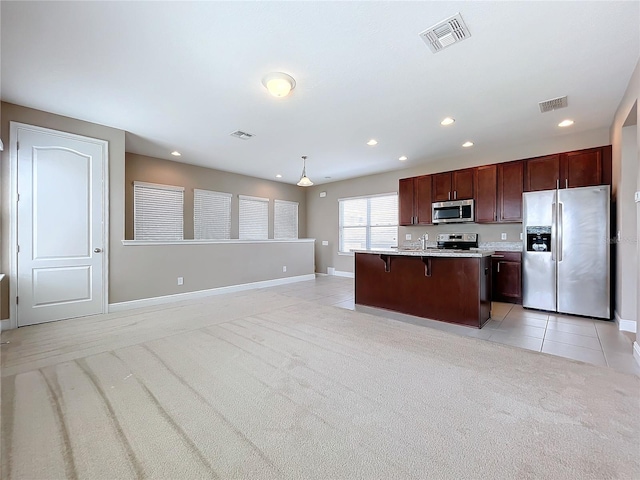 kitchen with light carpet, hanging light fixtures, a center island with sink, and stainless steel appliances