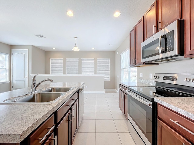 kitchen featuring appliances with stainless steel finishes, sink, a center island with sink, light tile patterned flooring, and hanging light fixtures