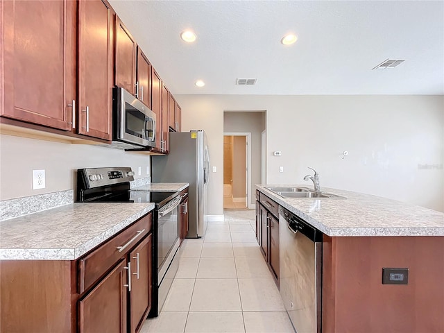 kitchen featuring light tile patterned floors, appliances with stainless steel finishes, sink, and a center island with sink