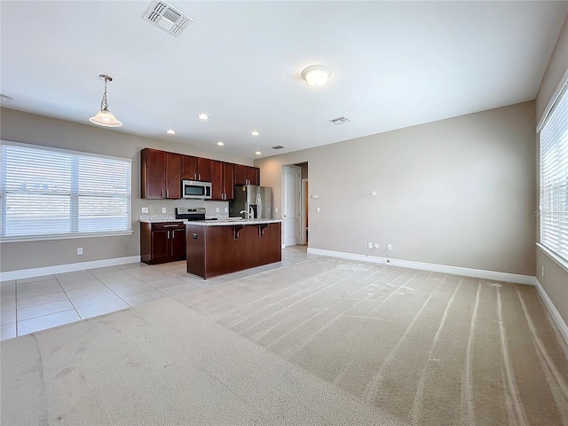 kitchen with light carpet, hanging light fixtures, an island with sink, a wealth of natural light, and stainless steel appliances