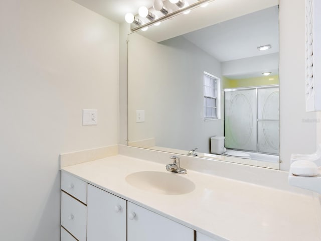 bathroom with a shower with shower door and vanity