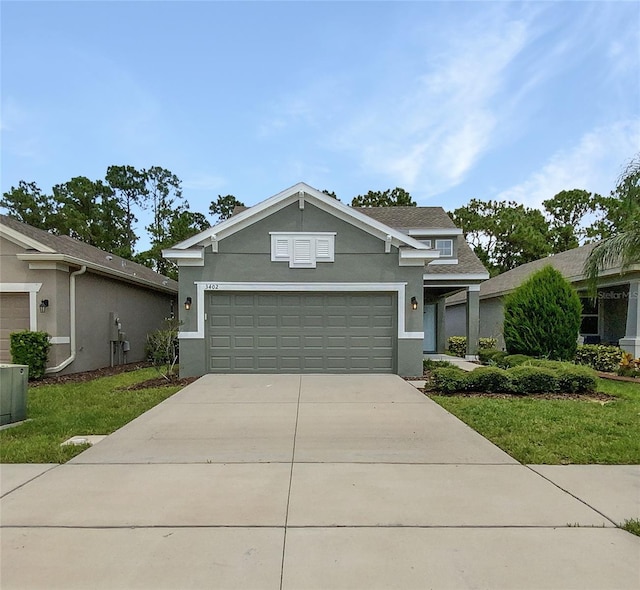 view of front of property with concrete driveway, a front yard, an attached garage, and stucco siding