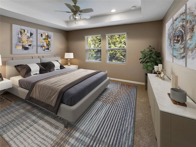 carpeted bedroom featuring ceiling fan and a tray ceiling