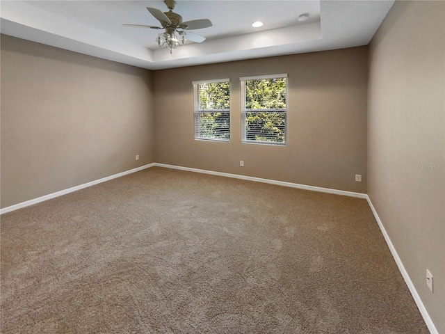 carpeted spare room with baseboards, a tray ceiling, ceiling fan, and recessed lighting