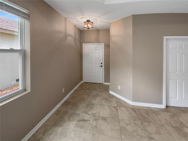 foyer entrance with light tile patterned floors, an inviting chandelier, and baseboards