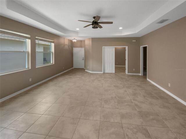 unfurnished room featuring ceiling fan, light tile patterned flooring, and a raised ceiling