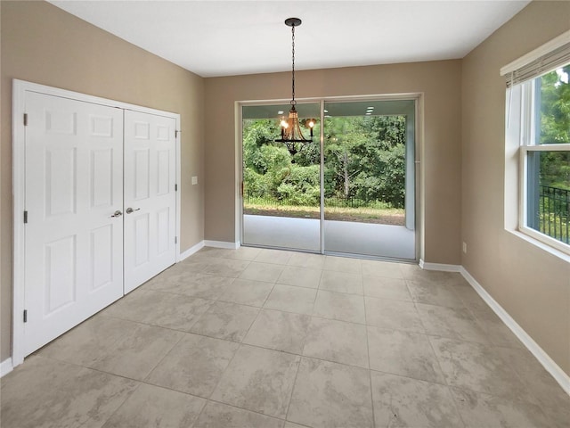 unfurnished dining area featuring an inviting chandelier, baseboards, and light tile patterned flooring