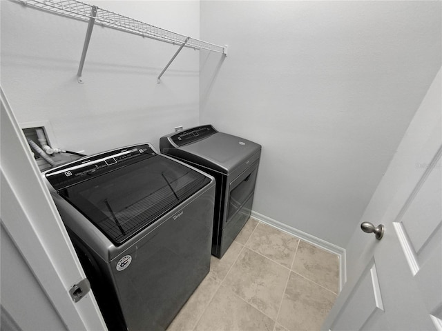 laundry area with light tile patterned floors, laundry area, independent washer and dryer, and baseboards