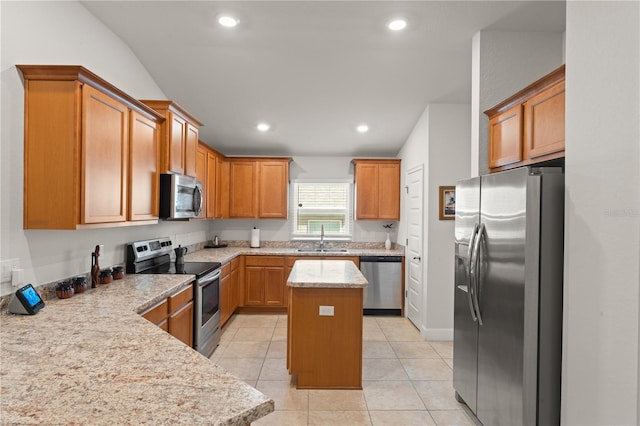 kitchen with a kitchen island, appliances with stainless steel finishes, light stone counters, sink, and light tile patterned flooring