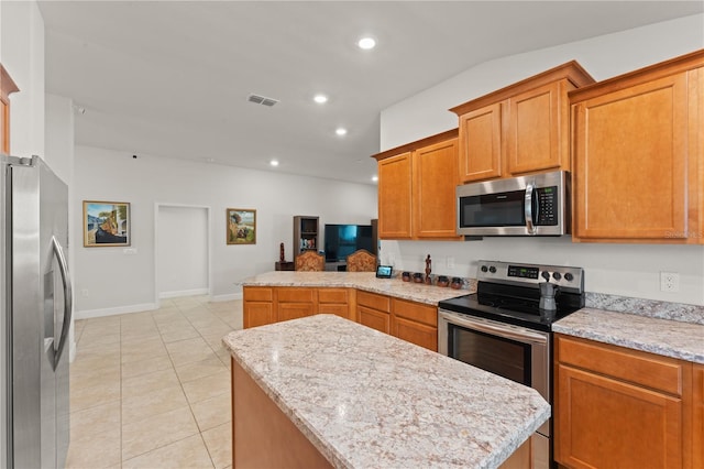 kitchen featuring appliances with stainless steel finishes, kitchen peninsula, light stone countertops, a kitchen island, and light tile patterned flooring