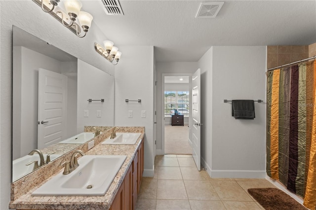 bathroom with a chandelier, double vanity, tile patterned flooring, and a textured ceiling