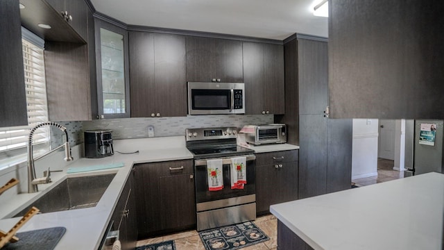 kitchen with dark brown cabinetry, sink, appliances with stainless steel finishes, and tasteful backsplash