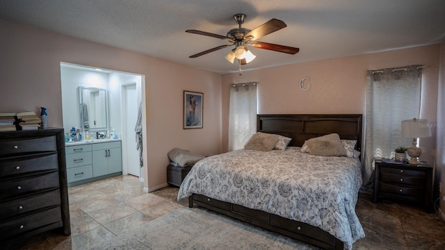 bedroom with ceiling fan, a textured ceiling, and ensuite bath