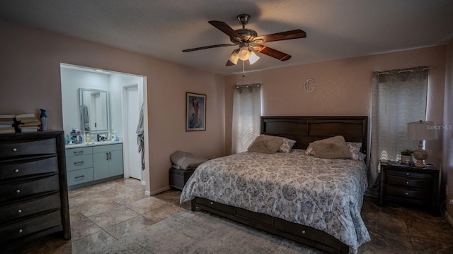 bedroom featuring ceiling fan, ensuite bathroom, and a textured ceiling