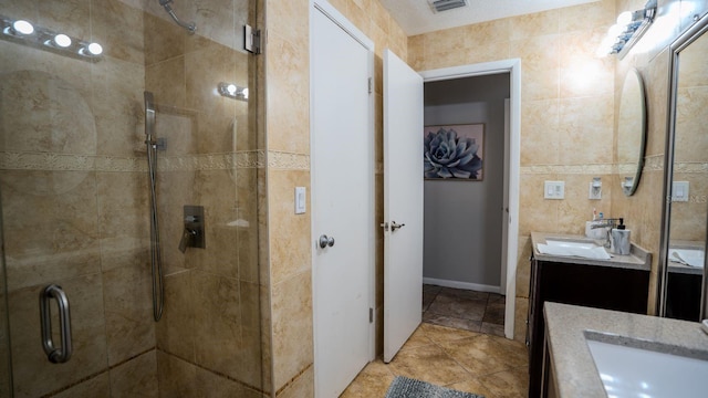 bathroom featuring vanity, tile patterned floors, tile walls, and a shower with shower door