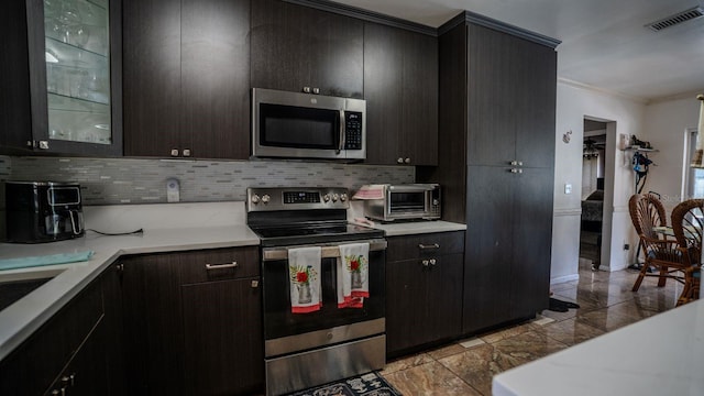 kitchen featuring stainless steel appliances, tasteful backsplash, and ornamental molding