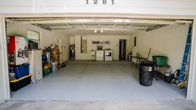 garage featuring electric water heater, a garage door opener, and washing machine and clothes dryer