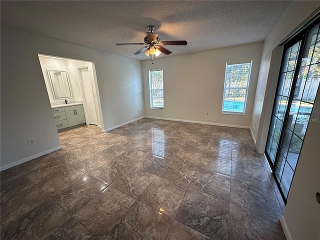 unfurnished room with a textured ceiling, plenty of natural light, and ceiling fan