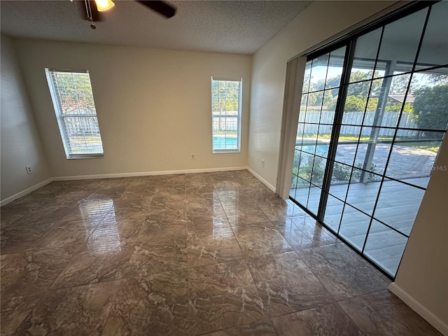 unfurnished room with a wealth of natural light, a textured ceiling, and ceiling fan