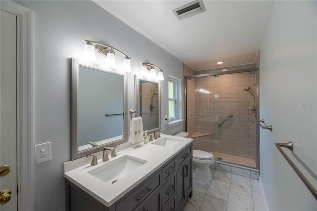 bathroom featuring dual vanity, toilet, tile patterned floors, and tiled shower