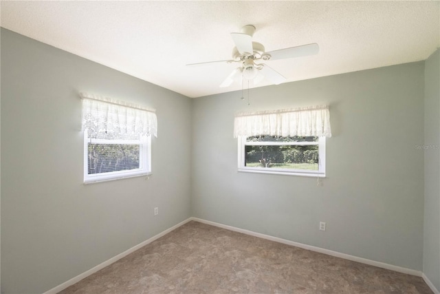 carpeted spare room featuring ceiling fan and plenty of natural light