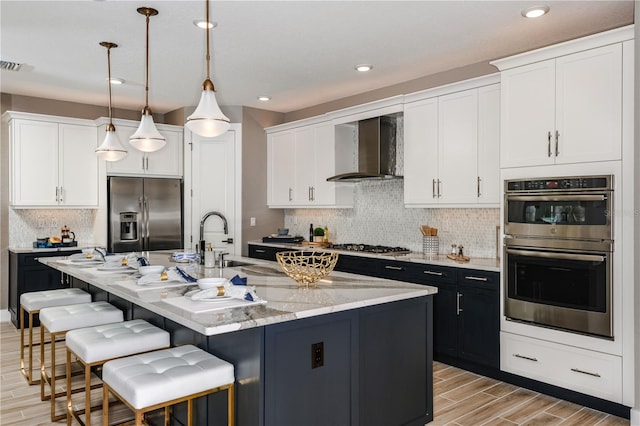 kitchen featuring stainless steel appliances, pendant lighting, decorative backsplash, and wall chimney exhaust hood