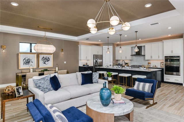 living room featuring light wood-type flooring and a tray ceiling