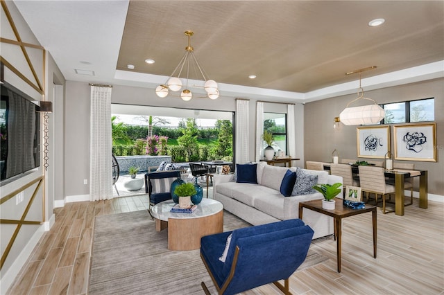 living room with a notable chandelier, light hardwood / wood-style flooring, and a tray ceiling