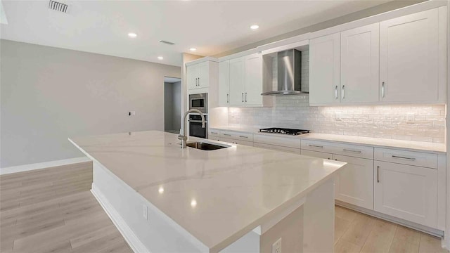 4910 Carova Way, Lakewood Ranch, FL 34211 - kitchen with decorative backsplash, light wood-type flooring, wall chimney exhaust hood, a sink, and stainless steel appliances