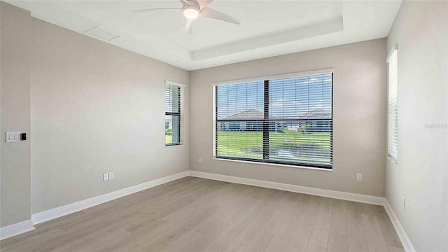 4910 Carova Way, Lakewood Ranch, FL 34211 - empty room featuring baseboards, ceiling fan, a tray ceiling, and wood finished floors