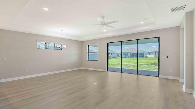 4910 Carova Way, Lakewood Ranch, FL 34211 - spare room with light wood finished floors, ceiling fan with notable chandelier, baseboards, a tray ceiling, and visible vents
