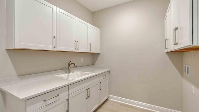 4910 Carova Way, Lakewood Ranch, FL 34211 - laundry room with baseboards, a sink, cabinet space, and light wood-type flooring