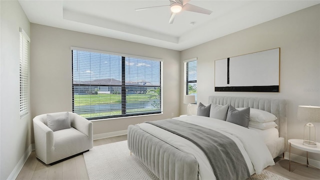 4910 Carova Way, Lakewood Ranch, FL 34211 - bedroom with baseboards, a raised ceiling, light wood-style floors, and ceiling fan