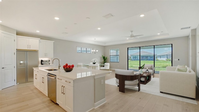 4910 Carova Way, Lakewood Ranch, FL 34211 - kitchen with visible vents, open floor plan, a sink, light wood-style flooring, and appliances with stainless steel finishes