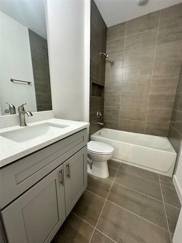 full bathroom with tiled shower / bath, toilet, tile patterned floors, and vanity