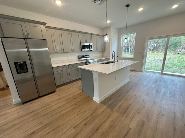 kitchen with sink, light wood-type flooring, gray cabinets, pendant lighting, and stainless steel appliances