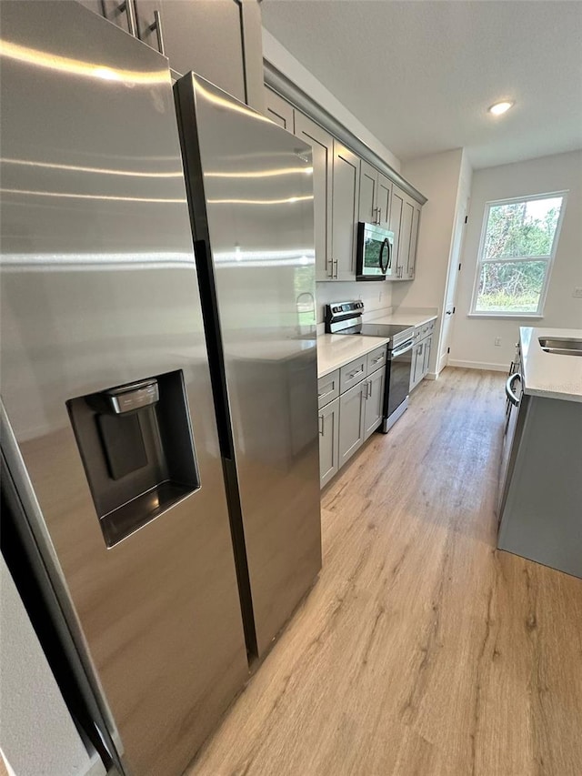 kitchen featuring appliances with stainless steel finishes, sink, light hardwood / wood-style floors, and gray cabinetry