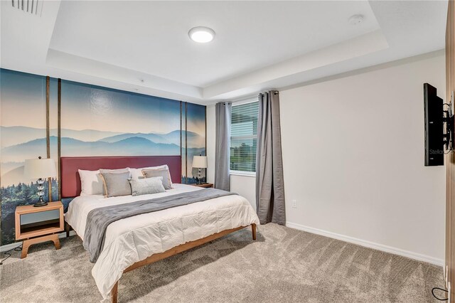 bedroom with visible vents, baseboards, a tray ceiling, and carpet flooring